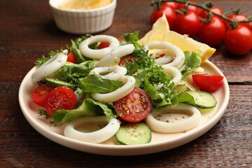 Delicious salad with squid rings, vegetables and spices served on wooden table, closeup