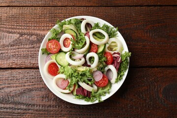Delicious salad with squid rings and vegetables on wooden table, top view