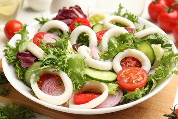 Delicious salad with squid rings and vegetables on table, closeup