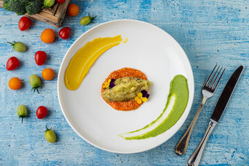 Eggplant puree with colorful sauces and edible flower garnish