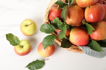 Fresh ripe apples in basket on white table, closeup
