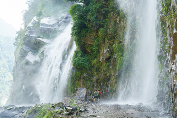 Hikers stand beneath a powerful waterfall