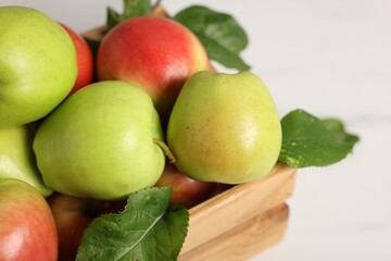 Fresh ripe apples in crate on white table, closeup