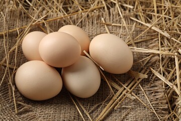 Raw chicken eggs and straw on table, closeup