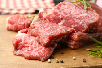 Pieces of raw beef meat and spices on table, closeup