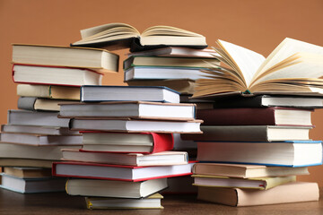Many stacked books on table against brown background
