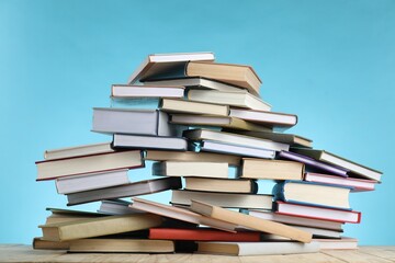 Many books on wooden table against light blue background