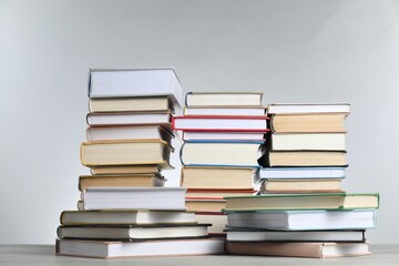 Many stacked books on table against light grey background