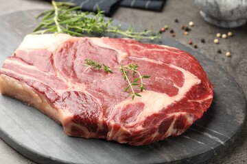 Piece of raw beef meat and spices on grey table, closeup