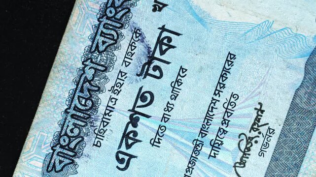 Bangladesh 100 Taka banknote obverse with Bengali script detail rotating on black background