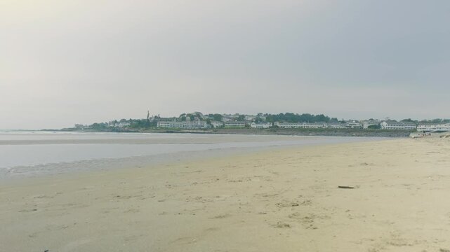 Low tide at Ogunquit Beach Maine with view of Marginal Way under an overcast foggy sky.