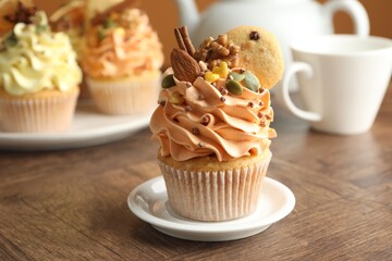 Delicious cupcakes with colorful cream and decor on wooden table, closeup