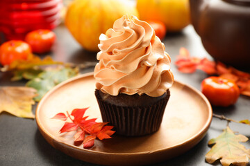 Delicious cupcake and autumn leaves on grey table, closeup