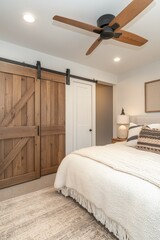 Cozy bedroom with barn doors, fan, and neutral decor