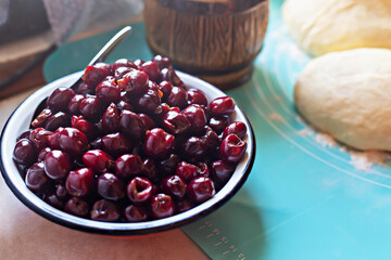 Cooking pies. Fresh cherries are beautifully arranged in bowl on turquoise countertop, with soft dough prepared for pie baking nearby, creating vibrant and inviting cooking scene