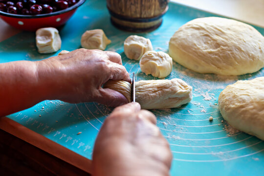 Cooking pies. Hands of elderly baker are expertly slicing dough into small pieces on turquoise surface, surrounded by fresh ingredients, showcasing art of pie making and joy of cooking - Powered by Adobe