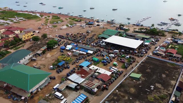 Aerial view over Coron town waterfront with rows of tricycles parked around a covered market area and boats anchored along the bay