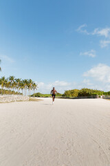 Muscular man jogging on the sandy streets of Miami under a bright blue sky