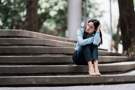 Young woman feeling sad, sitting alone on stairs