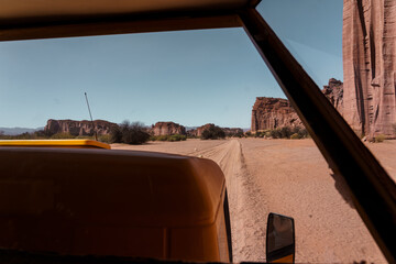 Desert canyon view from inside a vehicle driving on a dirt road