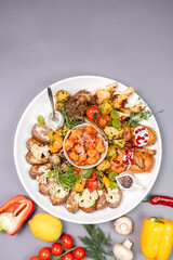 Flat lay: assorted meat, vegetables, and appetizers on a white plate.
