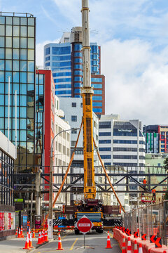 A towering yellow construction crane operates in a busy central Wellington street