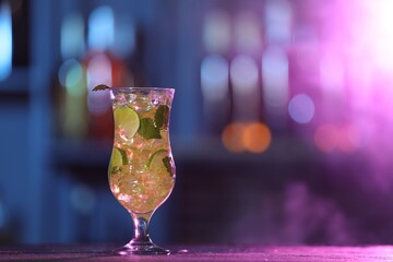Glass of alcoholic cocktail on table against blurred background, space for text