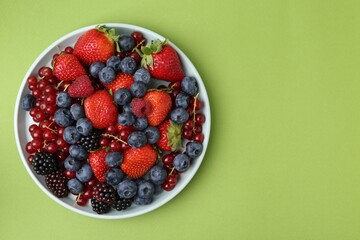Different ripe berries on green background, top view. Space for text