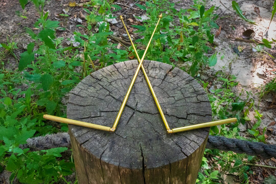 Dowsing with metal indicator L rods is a modern tool of a dowser. Two dowsing rods for the radiesthesia technique, lie on the stump of an old tree. An ancient method, not scientifically proven