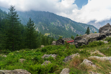 Abandoned stone shelter with stones above and hill on the background above Balme village in Graian Alps in Italy