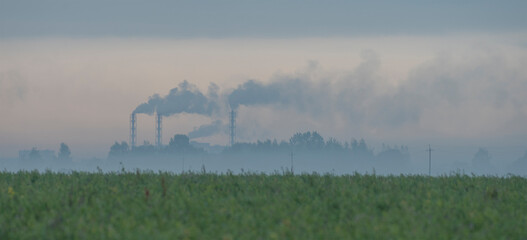 a factory in the distance. Smoking chimneys