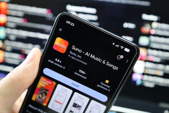 Hand holding cellphone with logo artificial intelligence company Suno AI Music & Songs app in front of business webpage. Focus on phone display