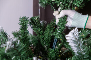 assembling an artificial christmas tree with gloves for secure and easy setup at home during holiday preparation