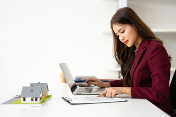 Real estate agent professional reviewing documents while working on a laptop.