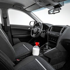 Clean car interior, gray seats, white spray bottle
