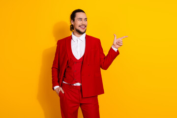 Confident man in a bright red suit smiles and points against a vibrant yellow background creating a...