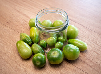 Green unripe tomatoes placed in a glass jar and around it, ready for ripening indoors. Natural way...