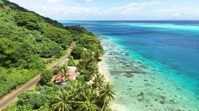 Huahine Island, French Polynesia. Drone Shot of Beach, Beachfront Homes, Road and Green Rainforest om Hills
