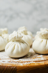 Raw khinkali on a cutting board with flour on the table. Concept of traditional Georgian cuisine. Vertical orientation. Selective focus.