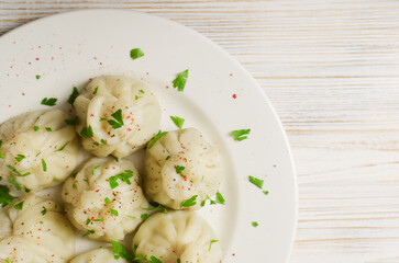 Boiled khinkali on a ceramic plate on a wooden table. Minimalism style. Traditional Georgian cuisine concept. Horizontal orientation. Selective focus. Top view. Copy space