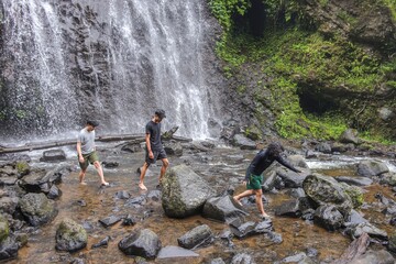 Young Friends Exploring Majestic Waterfall Feeling Adventurous And Connecting With Nature
