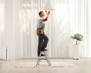 Worker climbing a ladder to change a light bulb