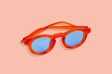 Orange stylish sunglasses with sky blue glasses isolated on colored background