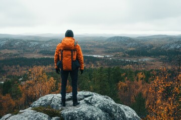 Fototapeta premium Hiker enjoying breathtaking view of autumn landscape from rocky elevation in serene wilderness