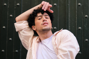 Young man posing with natural curly hair, expressing confidence and modern style