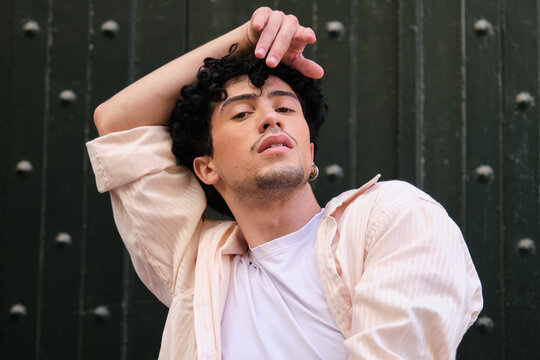 Young man posing with natural curly hair, expressing confidence and modern style