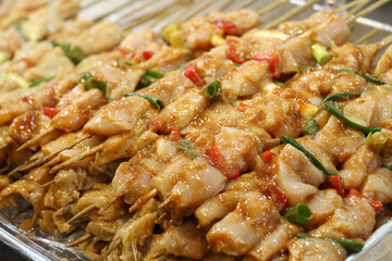 Marinated raw chicken skewers ready for grilling.
