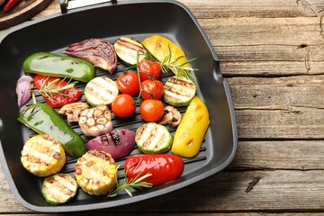 Pan with grilled vegetables and spices on wooden table, closeup. Space for text