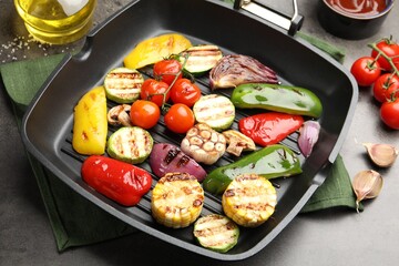 Pan with grilled vegetables and spices on grey table, closeup
