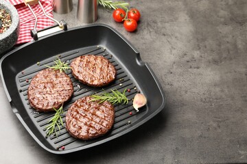 Pan with grilled patties, tomatoes and spices on grey table, closeup. Space for text